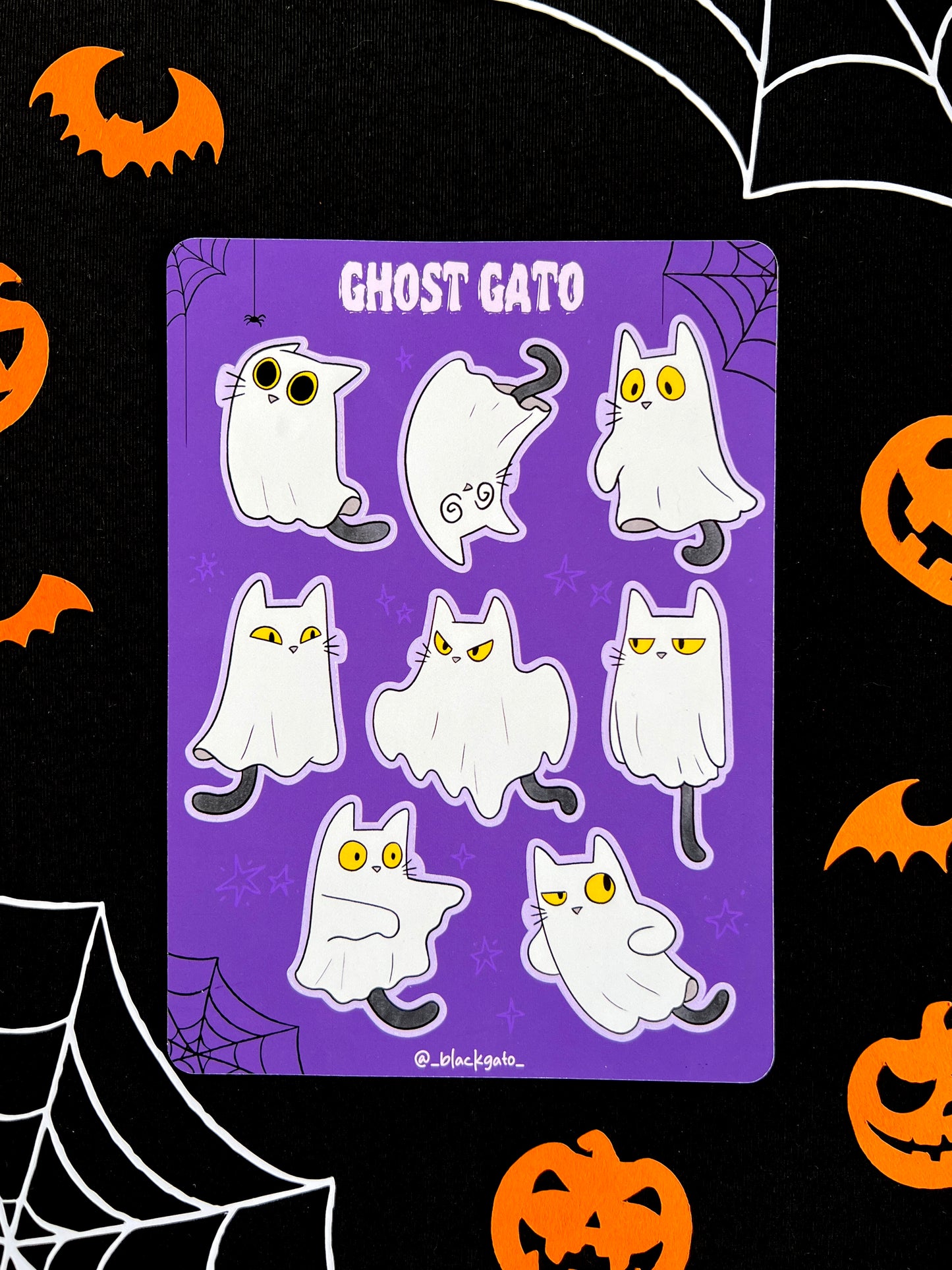 Purple sticker sheet with eight stickers of a black cat dressed as a ghost.