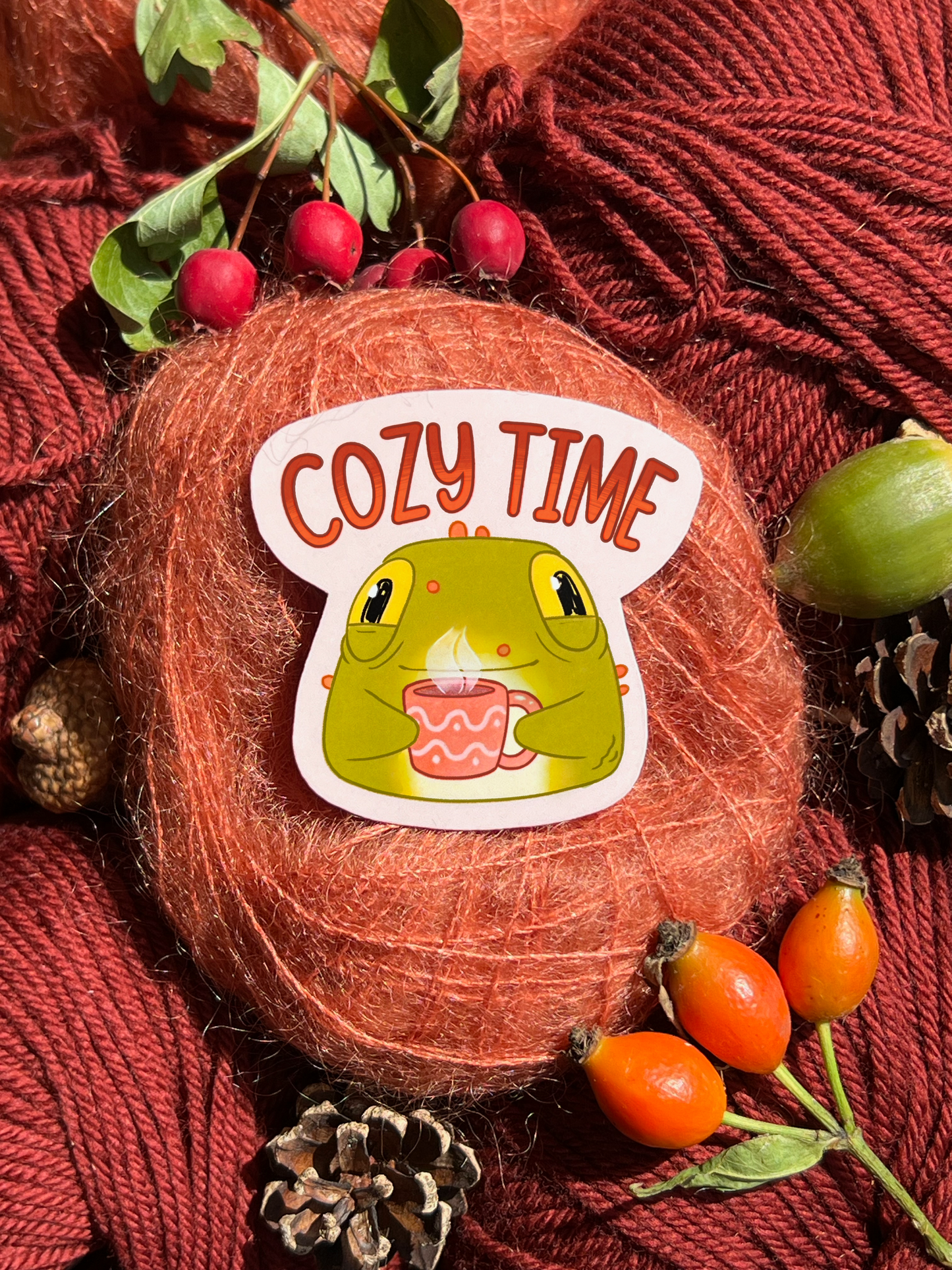 Toad sticker holding a mug on a cozy autumn themed background. The text on the product reads Cozy Time.