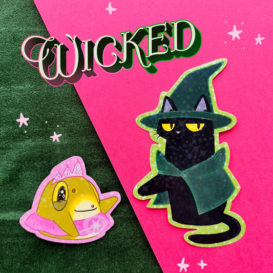 A set of two themed vinyl stickers inspired by the musical Wicked. The left sticker features a cute yellow Toad wearing a pink tiara and tutu, representing "Glinda." The right sticker portrays Blackgato, a black cat in a witch’s hat and green cape, as "Elphaba." The background contrasts green and pink, with the word "WICKED" written in a playful font above the stickers.